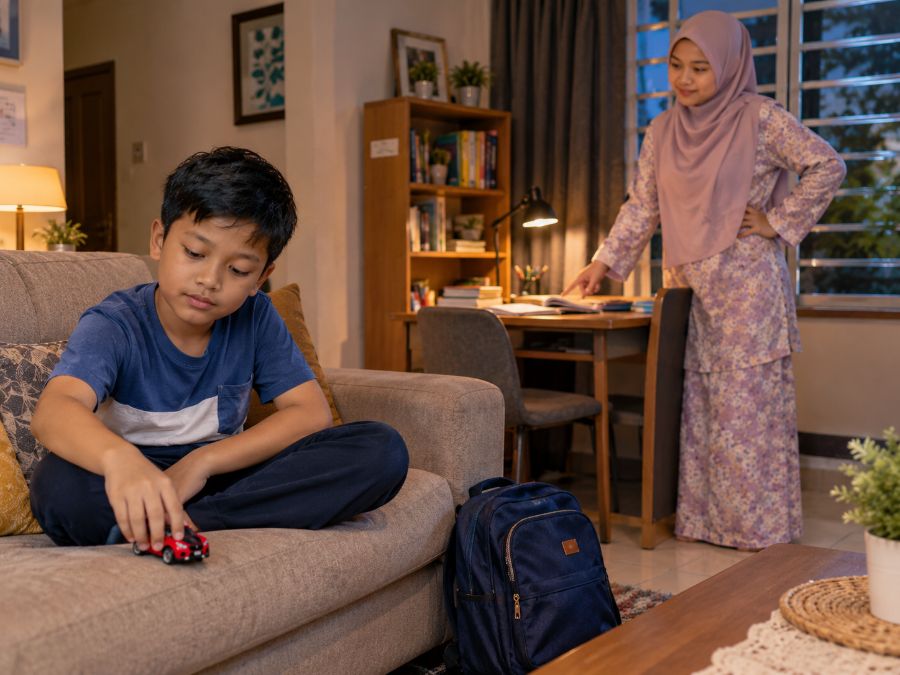 Anak bermain kereta mainan di sofa sementara ibu memanggilnya belajar